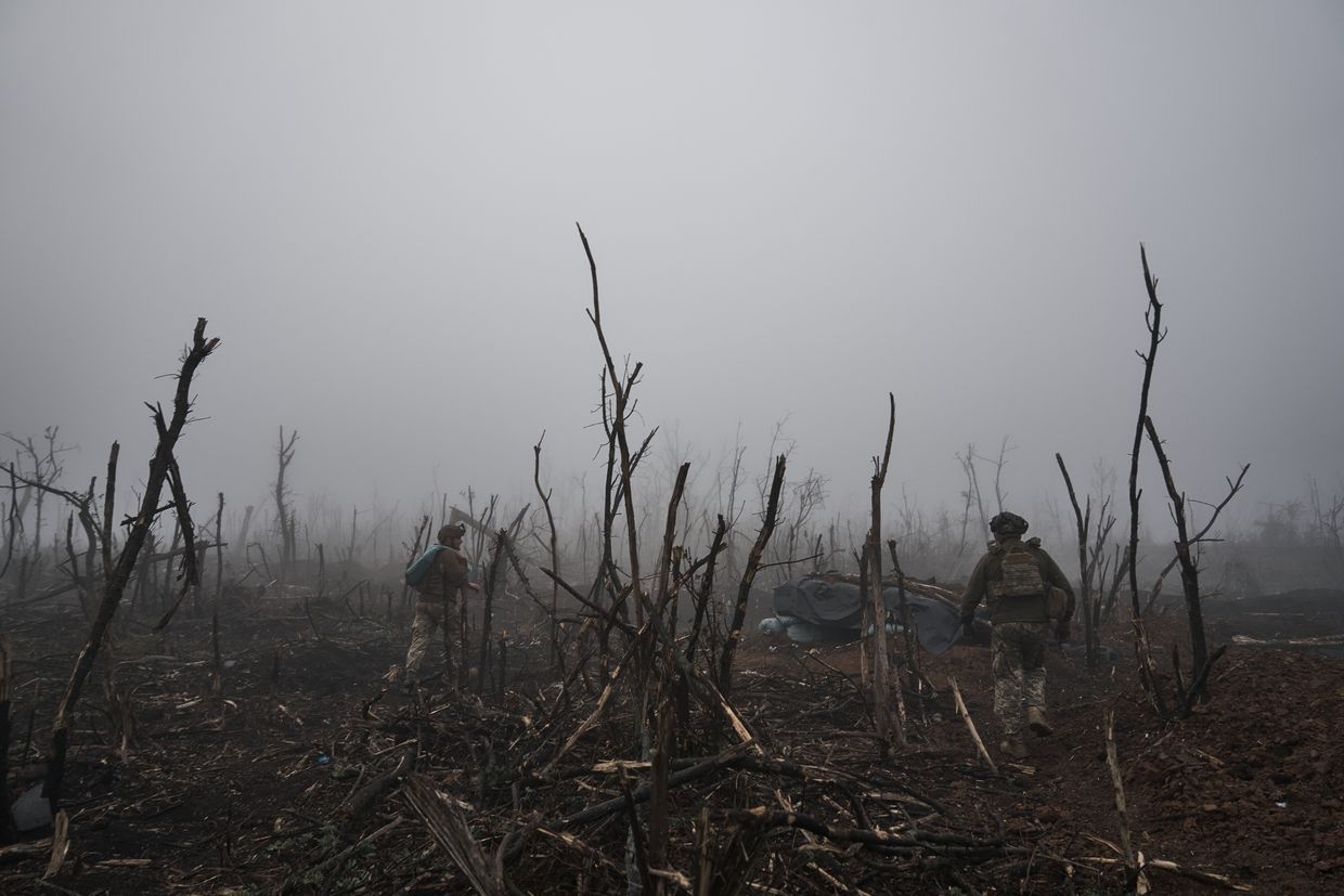 Two soldiers of the 10th Mountain Assault Brigade walk in fog among destroyed trees near Russian positions in Bakhmut, Ukraine, Oct. 25, 2023.