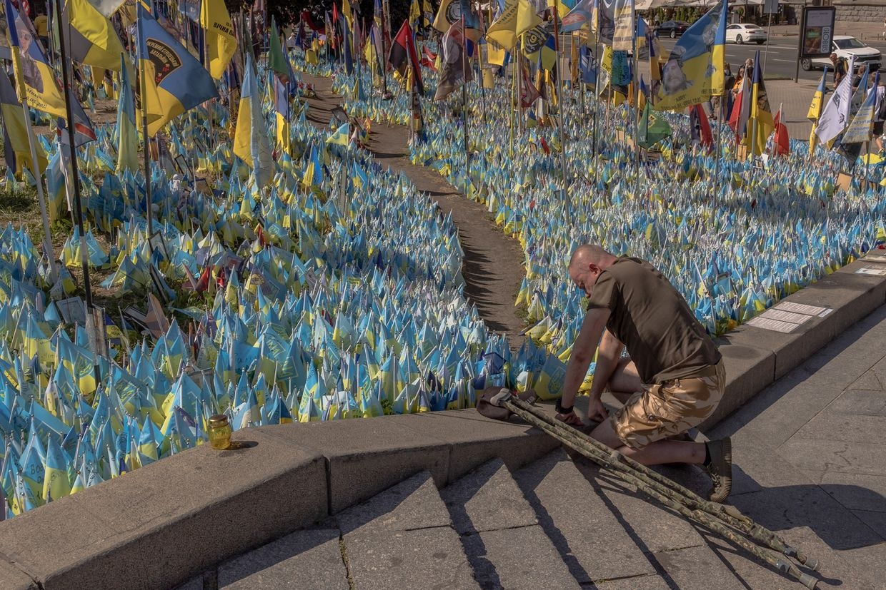 Ukrainian veteran Viacheslav Rybachuk kneels at Kyiv's Independence Square on Aug. 24, 2024, honoring fallen soldiers, including his brother Oleksiy.