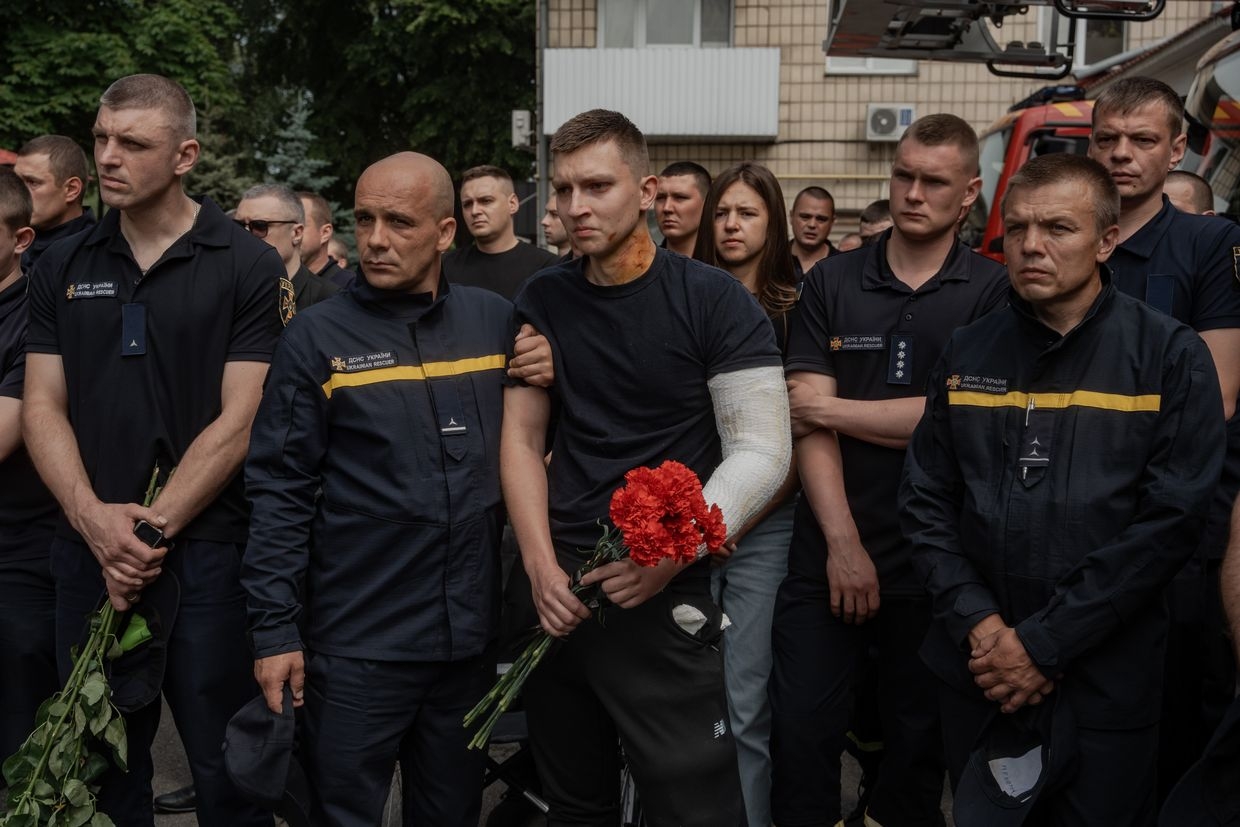 A wounded Ukrainian rescuer holds red carnations during a farewell ceremony for three emergency workers killed by a Russian missile strike in Kyiv, Ukraine, on June 9, 2025. 