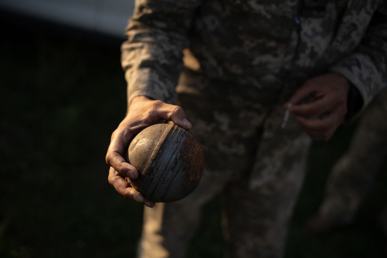 A soldier of a mobile anti-aircraft brigade holds an unexploded Russian cluster bomb in Starokostiantyniv, Khmelnytskyi Oblast, Ukraine, on July 8, 2024. 