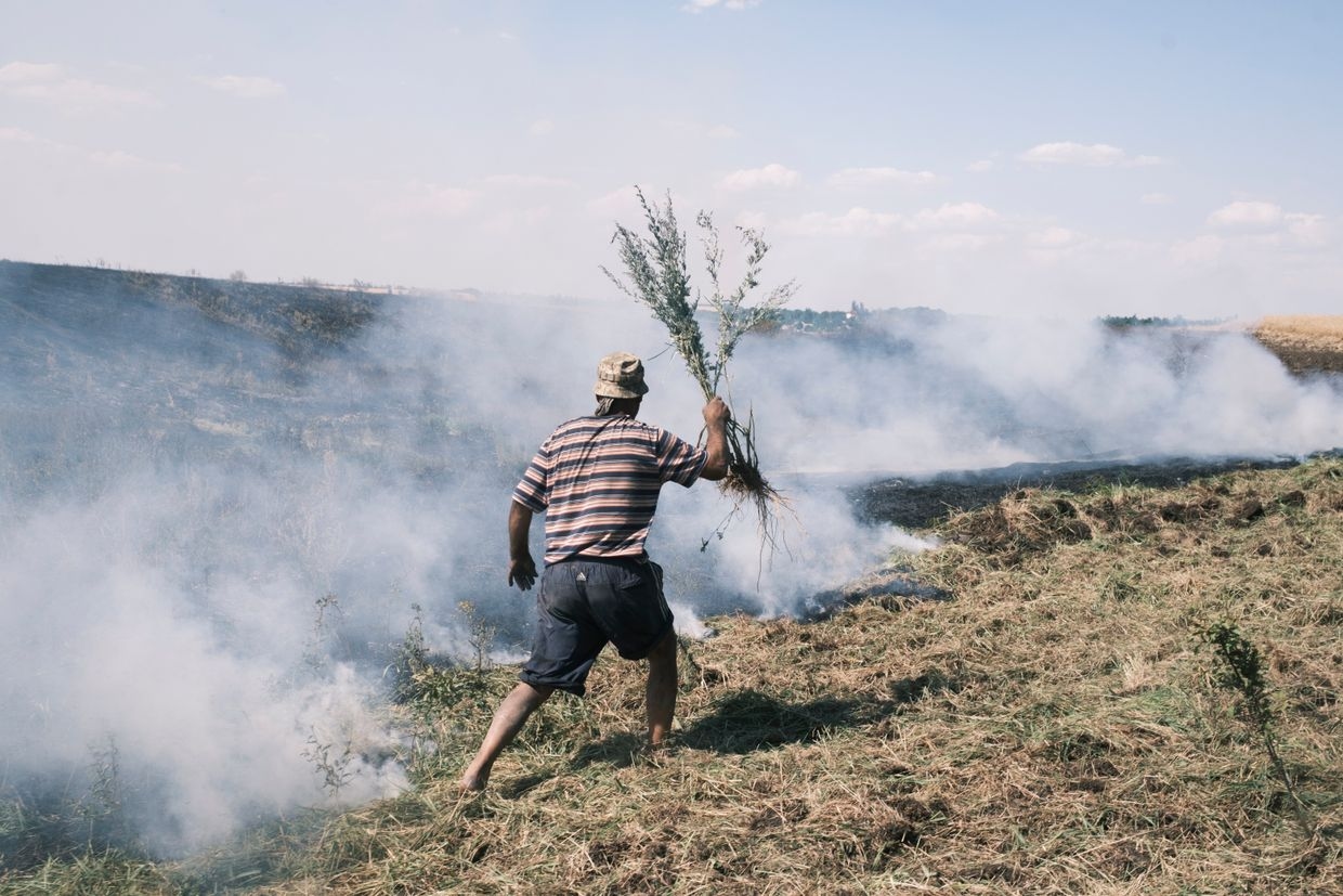 Local resident, helps to put out the fire in the wheat fields, burning after the shelling in the village of Nova Poltavka, Donetsk Oblast, Ukraine, July 2, 2024.