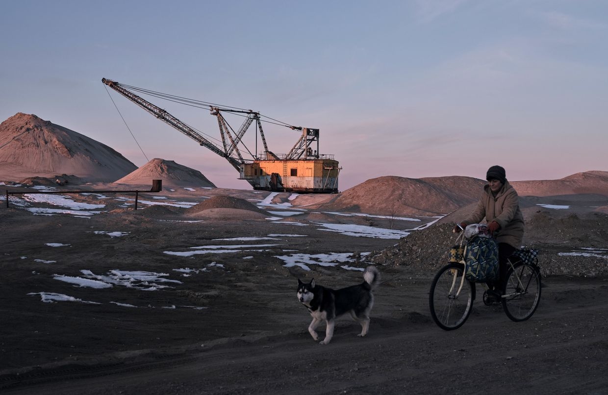 A woman cycles past with her dog as bucket-wheel excavators mine rare earth materials in Zhytomyr Oblast, Ukraine, on Feb. 25, 2025