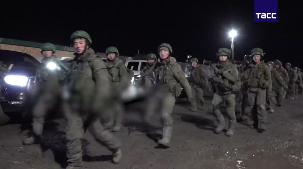 North Korean troops, wearing full Russian military uniforms and carrying rifles, are shown marching at night in footage released on April 28, 2025. (Screenshot from a video released by the Russian state news agency TASS)