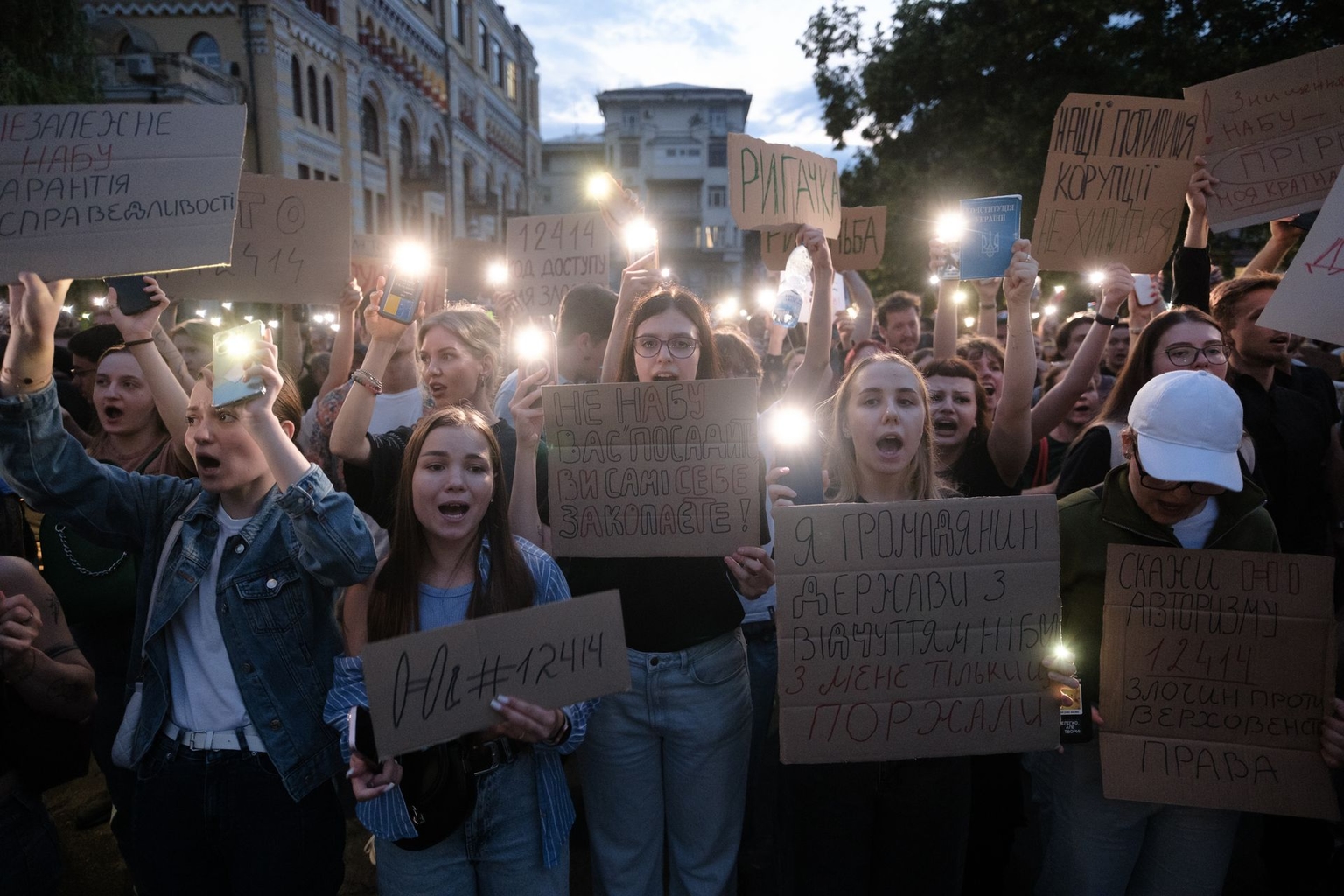 Protesters turn on flashlights and hold placards during a rally against a law restricting the independence of anti-corruption institutions in Kyiv, Ukraine, on July 22, 2025.