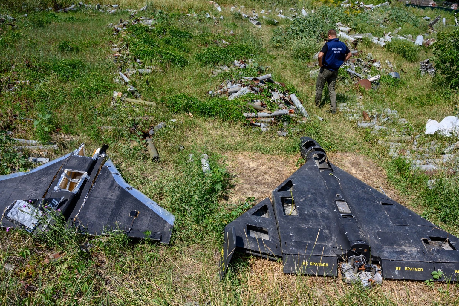 A person stands beside the remains of a Russian-made, Iran-designed Shahed-136 drone