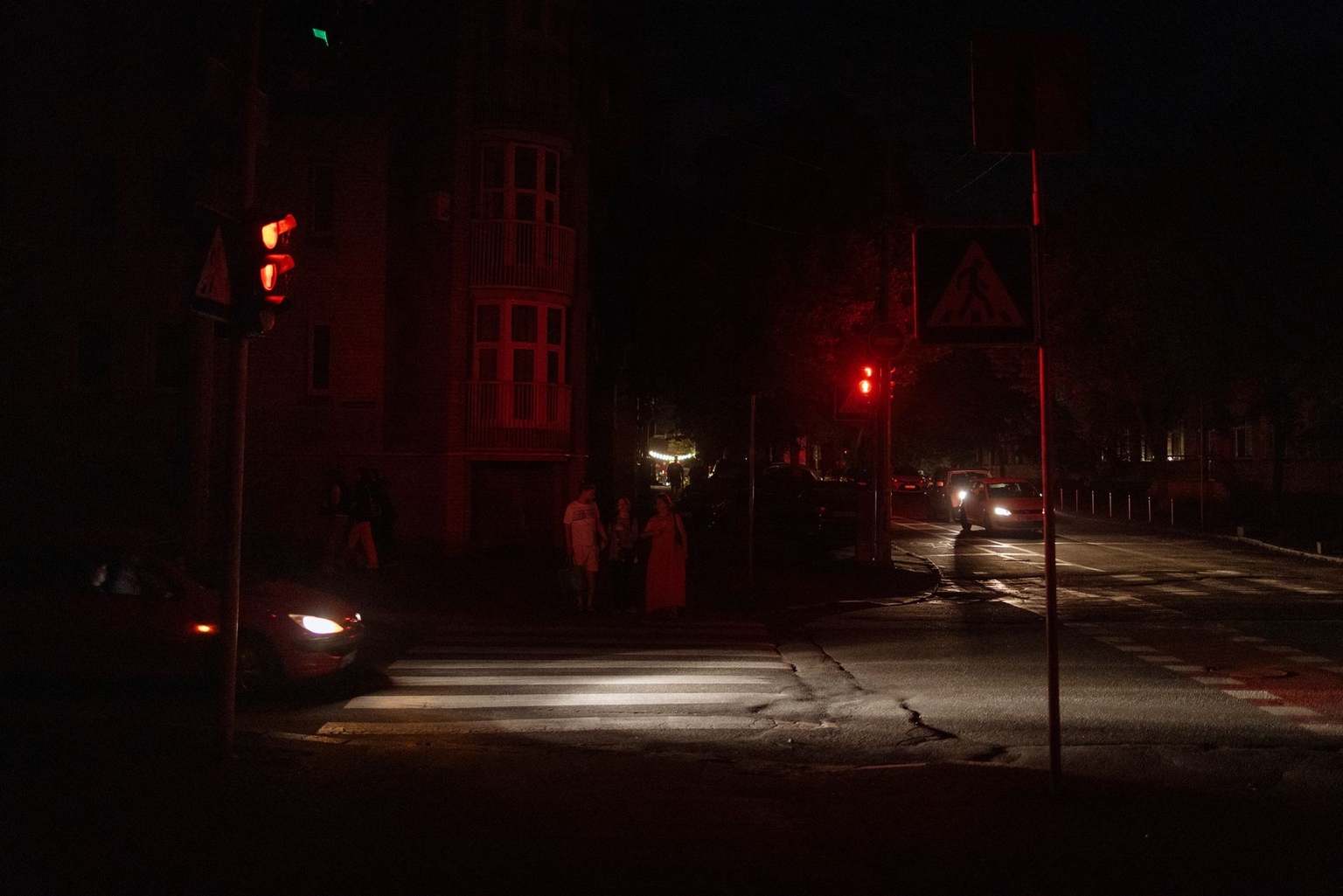 People walk along a darkened street during a partial electricity blackout following Russian strikes on Ukrainian energy infrastructure in the Podil neighborhood of Kyiv, Ukraine, on Aug. 28, 2024.