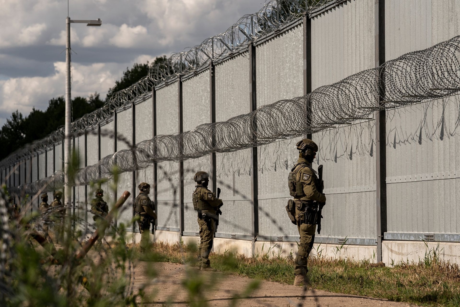Polish border guards stand by the border fence at the Poland-Belarus border near the village of Ozierany Male, Poland, on July 4, 2025.