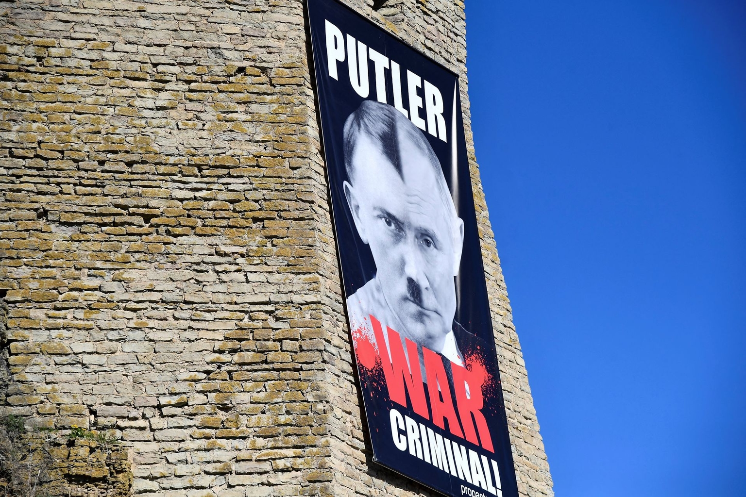 A banner depicting Russian President Vladimir Putin with the lettering “War criminal!” hangs on the wall of the Narva Museum in Narva, Estonia, on May 9, 2025.
