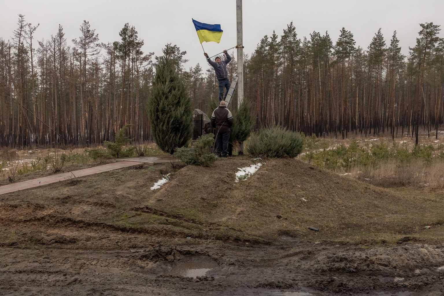 A man installs a Ukrainian flag on a memorial for Ukrainian soldiers in Kramatorsk District, Donetsk Oblast, Ukraine, on Jan. 19, 2024.
