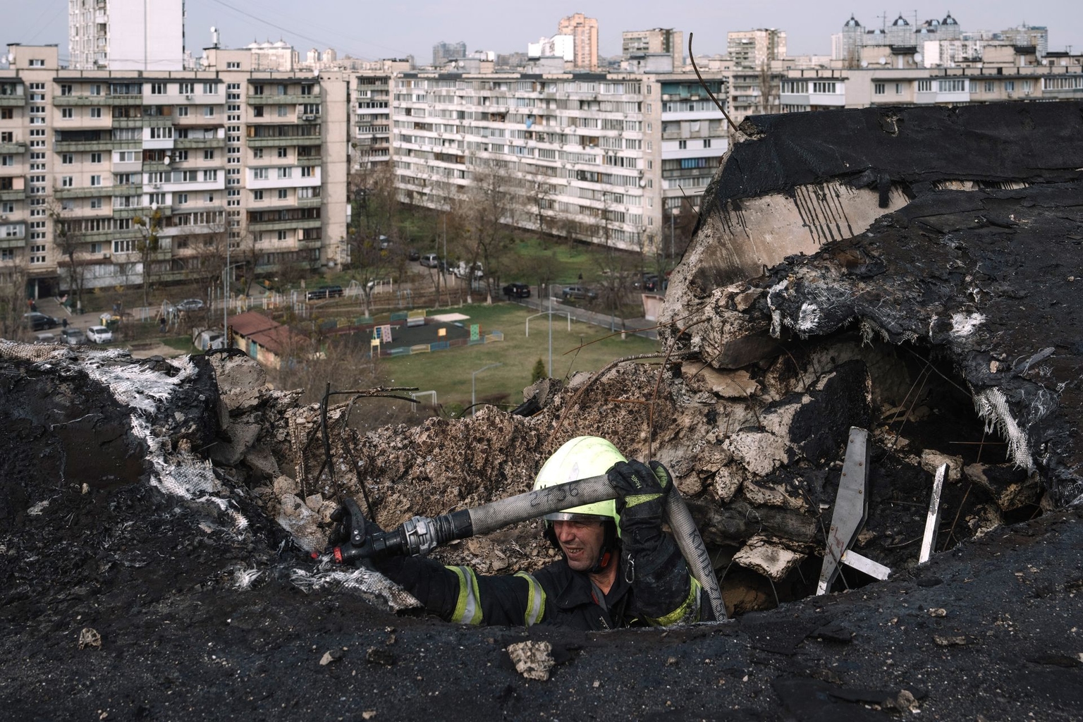A firefighter stands at the impact site on a residential building following a Russian night drone strike in Kyiv, Ukraine, on March 23, 2025, amid efforts toward a proposed mutual halt to strikes on energy assets.