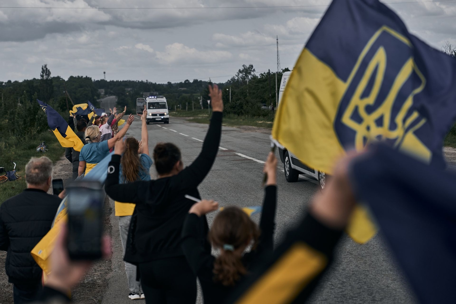 Local residents holding Ukrainian flags greet soldiers who returned from Russian captivity following a prisoner exchange between Ukraine and Russia.