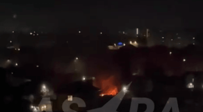 A fire burns in the cityscape under a dark night sky