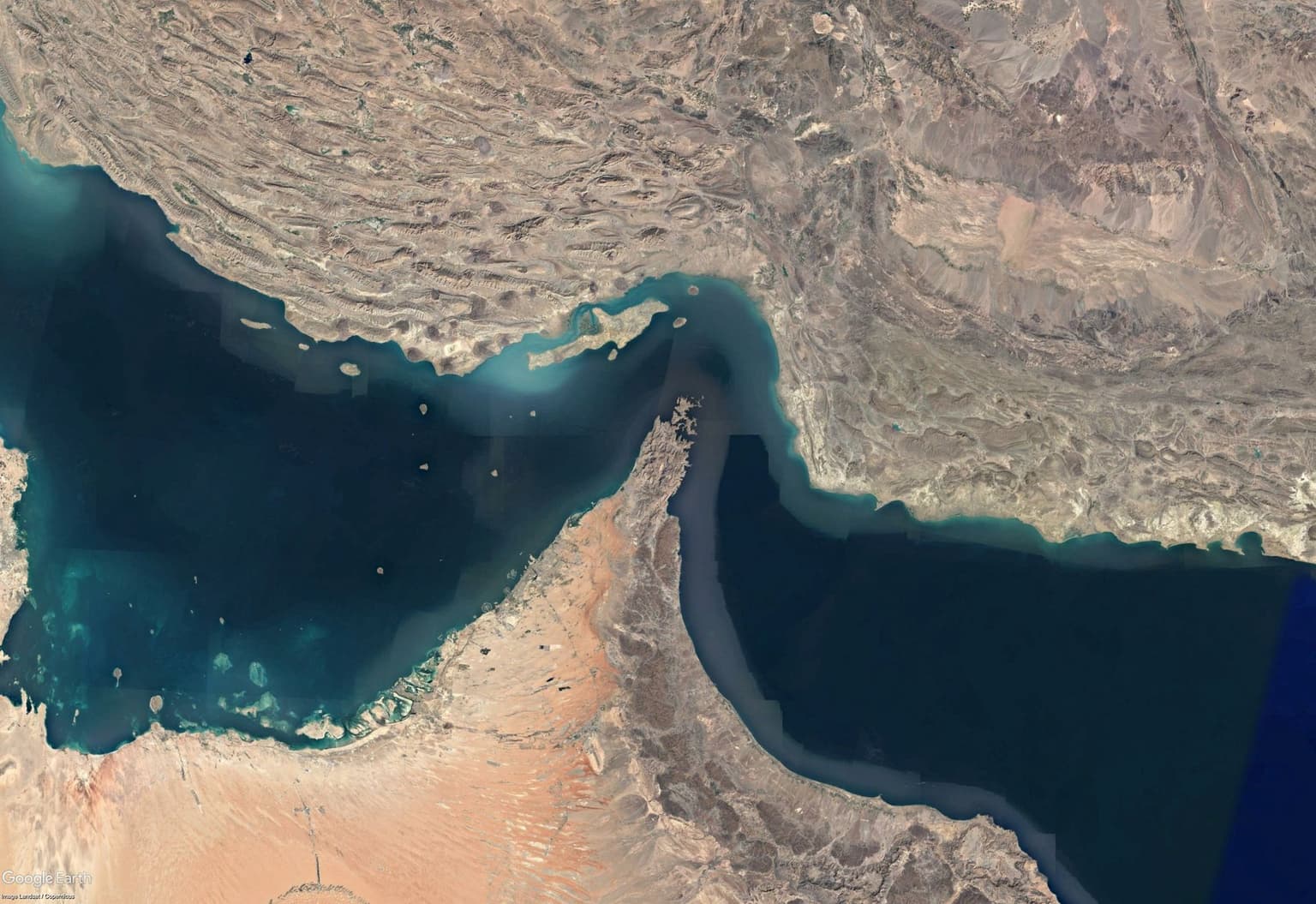 A Google Earth image shows the aerial view of the Strait of Hormuz, which links the Persian Gulf to the Arabian Sea.