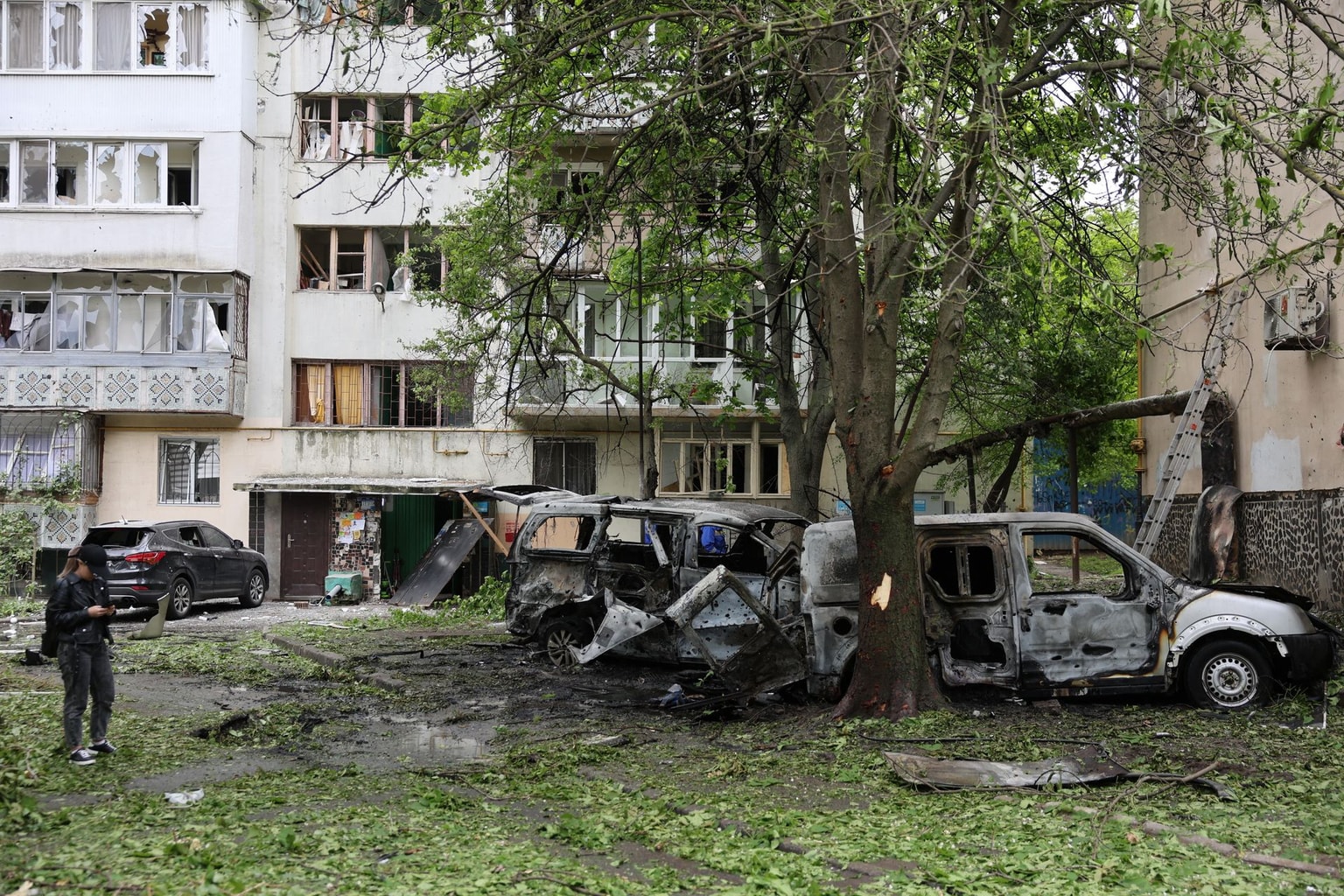 A woman stands next to destroyed cars in the courtyard of a damaged residential building following a drone attack in Odesa on May 13, 2026, amid the Russian invasion in Ukraine. (Oleksandr Gimanov / AFP via Getty Images)