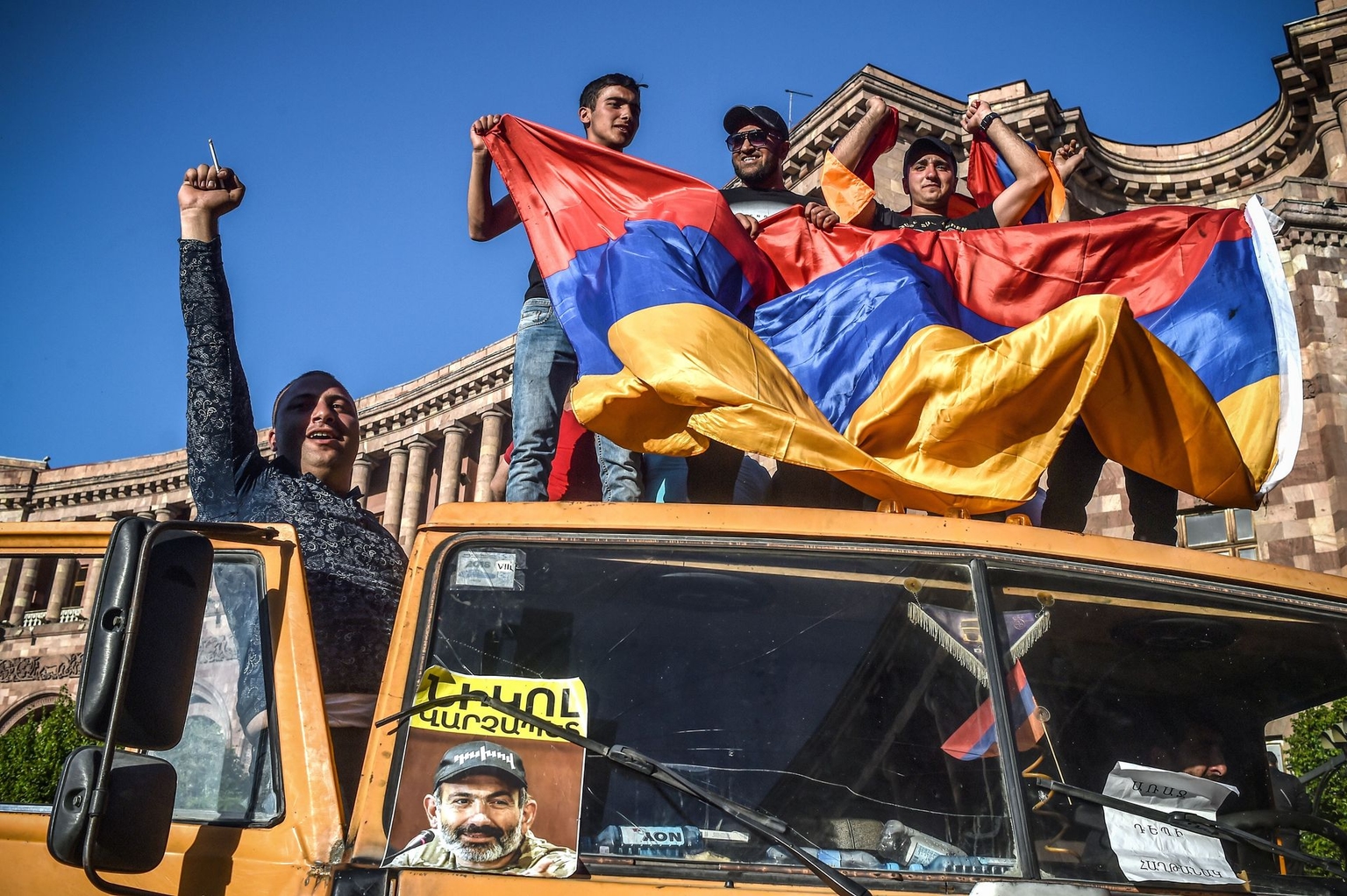 Protestors shout slogans and wave an Armenian national flag as they stand on a truck with a photograph of then-opposition leader Nikol Pashinyan in Yerevan, Armenia, on May 2, 2018.