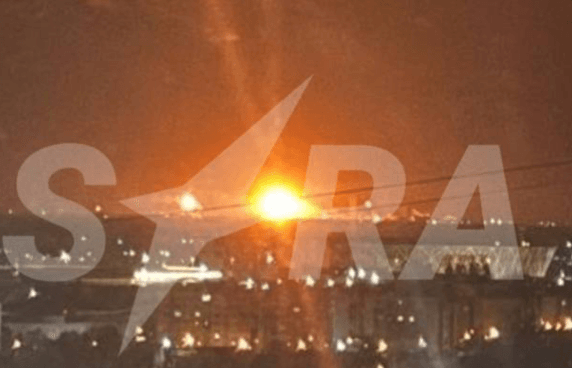 A bright orange explosion glows behind a cityscape