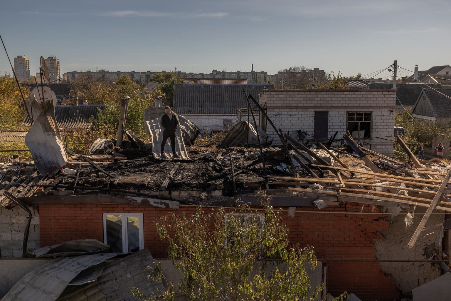 A man stands on the roof of a house damaged during an overnight Russian attack in Kherson, Ukraine, on October 30, 2023.