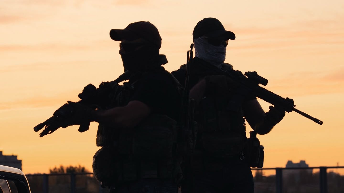 A pair of soldiers stand back-to-back as they hold their rifles in an undated photo.