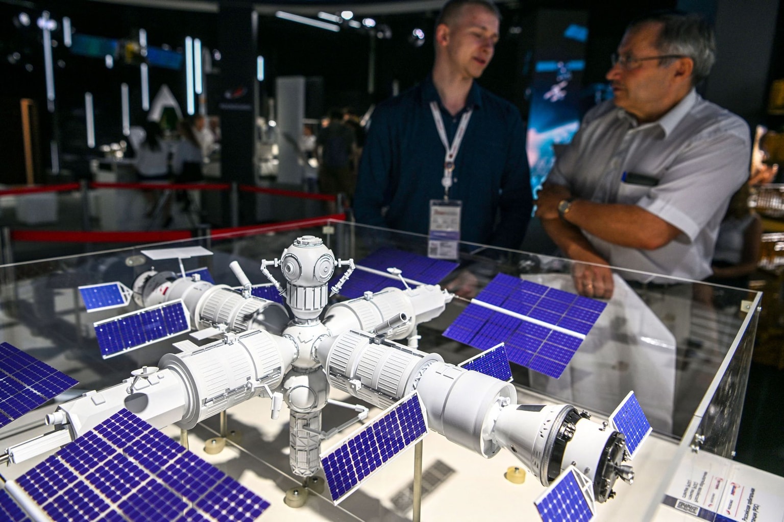 Visitors stand next to a mockup of a new Russian orbital space station, presented by Roscosmos State Space Corporation, during the Army-2022 International Military-Technical Forum at the Russian Armed Forces' Patriot Park in Kubinka, outside Moscow on August 16, 2022. (Natalia Kolesnikova/AFP via Getty Images)
