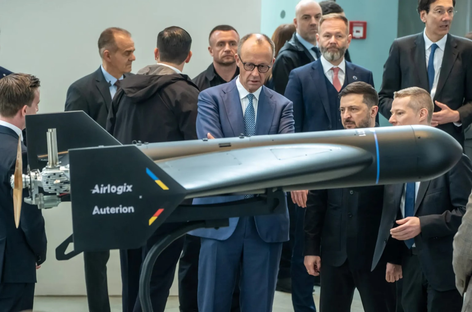 Auterion CEO Dr. Lorenz Meier, Airlogix CEO Vitalii Kolesnichenko, President Volodymyr Zelensky, and German Chancellor Friedrich Merz stand with an Airlogix autonomous strike system at the contract signing ceremony in April 2026. (Auterion)
