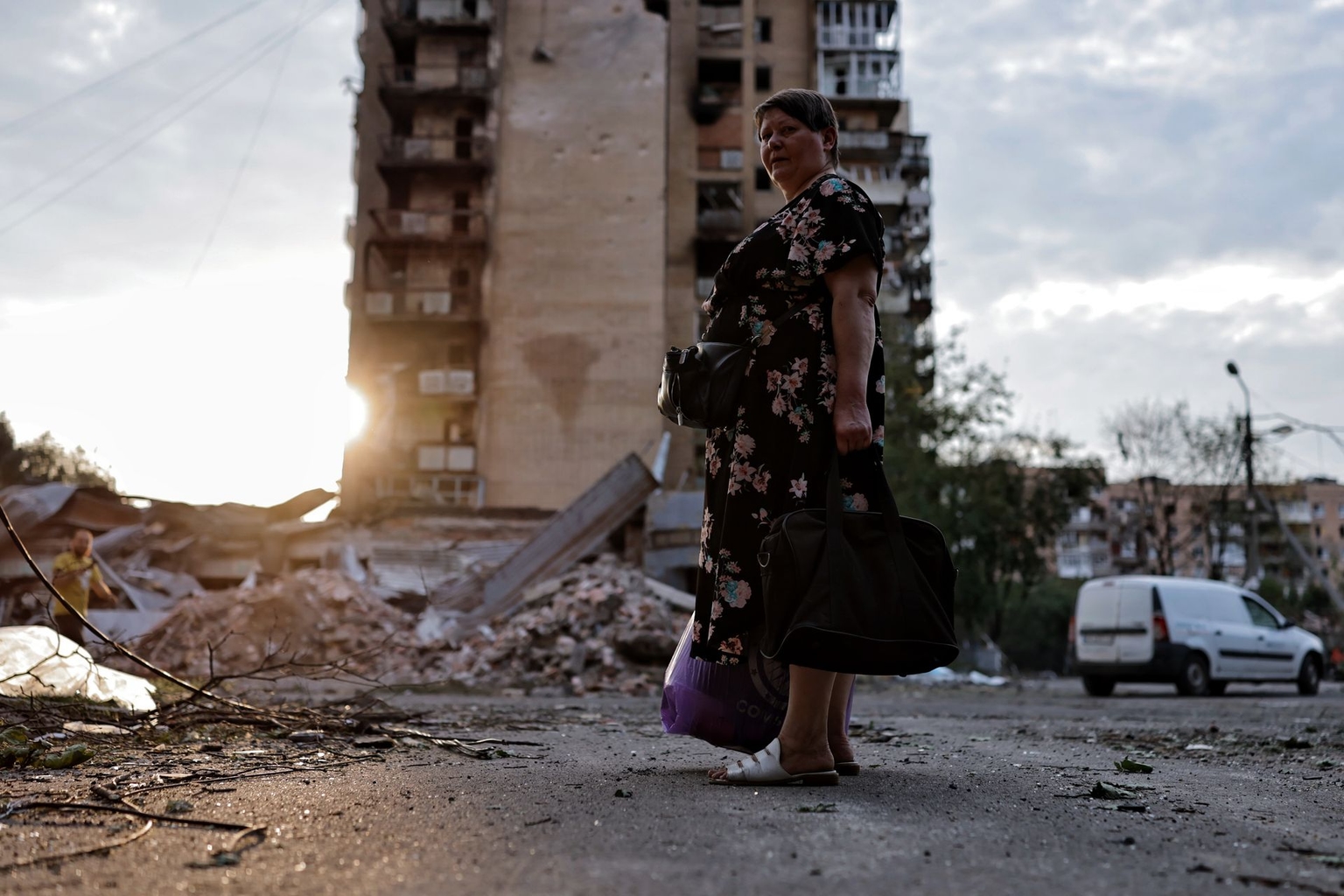 A woman with bags stands in front of a destroyed apartment building in Kramatorsk, Ukraine, on Aug. 5, 2026.